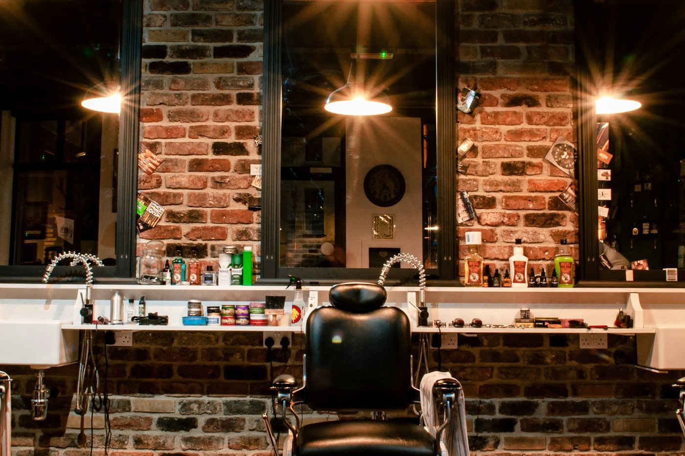 The row of barber's chairs and the mirrors along the brick wall, under the shop's pendant lamps