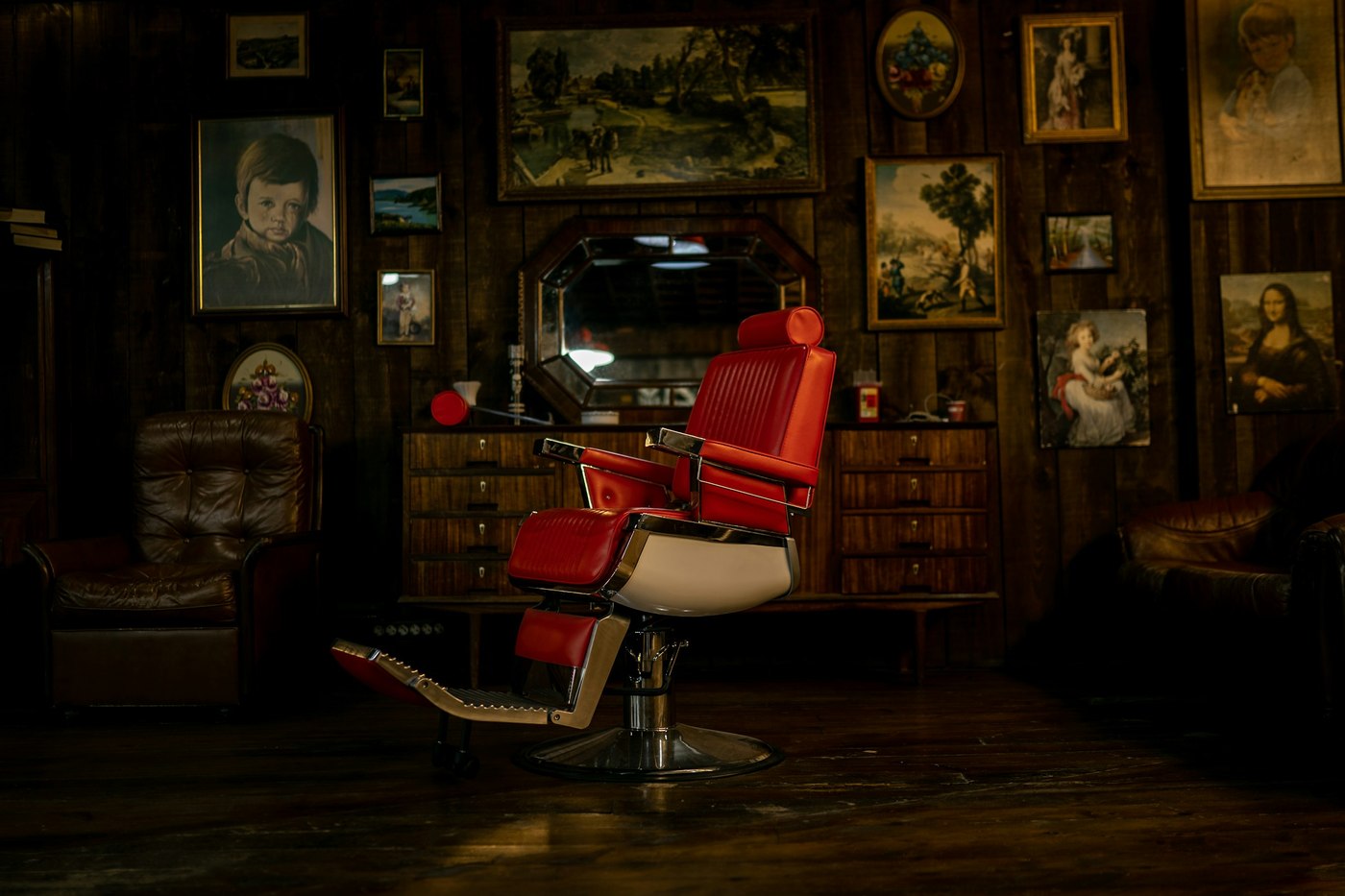 The red chair in the back room, the wall behind it hung with framed pictures
